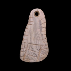 May include: A carved stone pendant with a hole at the top for hanging. The pendant is light gray with darker gray striations and carved lines. The shape is elongated with a rounded top and a wider bottom.