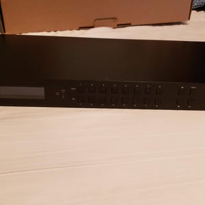 Puede incluir: Un conmutador matricial HDMI 8x8 negro con una pantalla y varios botones. El texto "NO HASSLE Audio/Video" est&aacute; impreso en el lado derecho. El dispositivo es rectangular y tiene orificios de montaje.