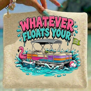 May include: A light beige tote bag with the phrase "WHATEVER FLOATS YOUR" in pink and turquoise lettering. The design includes a cartoon pontoon boat, a flamingo, and a beach ball, with the words "LAKE LIFE" on a green flag.