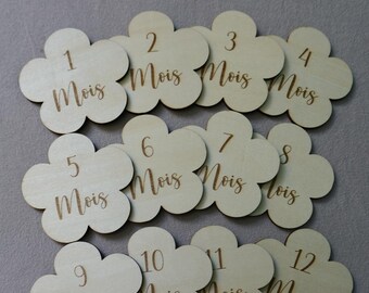 May include: Twelve wooden flower-shaped  baby milestone markers with the numbers 1 through 12 and the word "Mois" (French for "month") written on each.