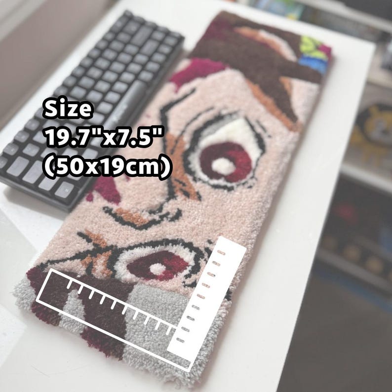 May include: A rectangular rug with a cartoon face design, measuring 19.7" x 7.5". The rug features a light pink background with brown, red, and white details. A black keyboard is visible in the background.