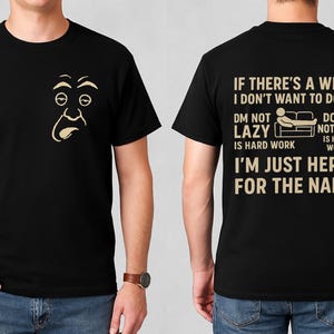 Può includere: T-shirt nero con una grafica di un volto di cartone animato sul davanti e testo sul retro. Il testo sul retro recita: "IF THERE'S A WILL I DON'T WANT TO DO IT. DM NOT LAZY IS HARD WORK. DOING NOTHING IS HARD WORK. I'M JUST HERE FOR THE NAPS."