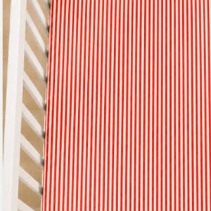 May include: A fitted crib sheet featuring a repeating pattern of thin vertical red and white stripes. The fabric is stretched taut across a white slatted crib frame, displaying a consistent and uniform linear design throughout the entire surface.
