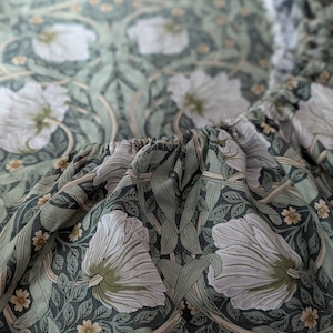 Puede incluir: Primer plano de una tela verde y blanca con un patrón floral. La tela presenta un diseño repetitivo de flores y hojas estilizadas.