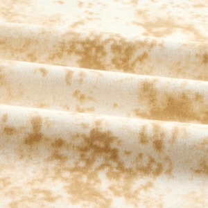 May include: A close-up of a white fabric with a brown tie-dye pattern. The fabric is soft and has a subtle texture.