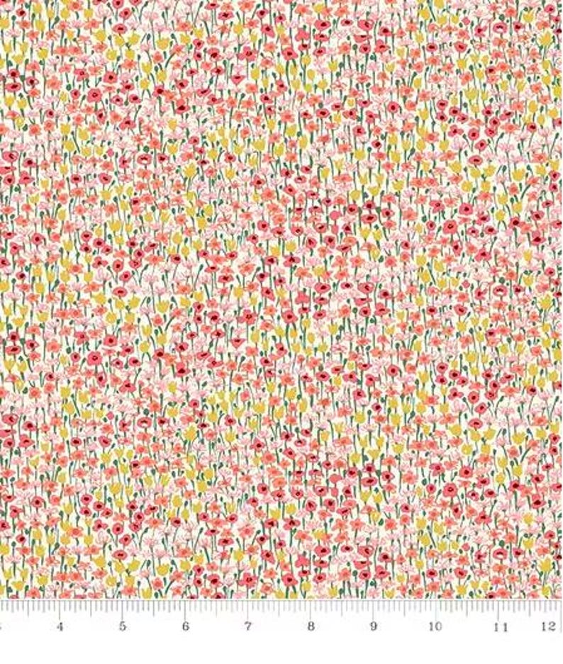 May include: A fabric with a floral pattern featuring small pink and yellow flowers on a cream background. The flowers have green stems and are densely packed, creating a field-like appearance. A ruler is at the bottom.
