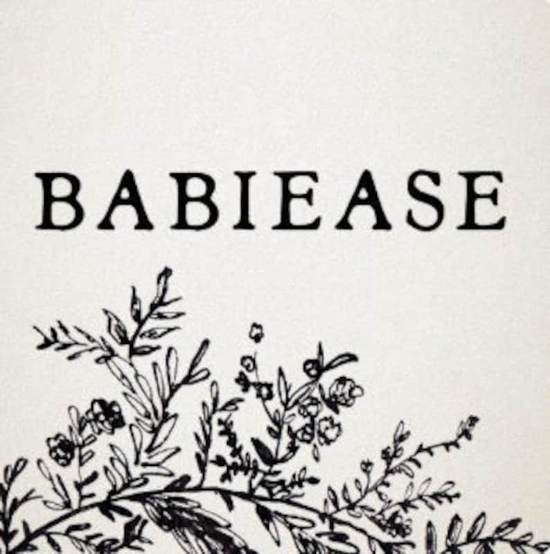 May include: Square, off-white print featuring the word "BABIEASE" in a bold, black serif font. A detailed black floral illustration adorns the bottom, with leaves and delicate blossoms. The design is simple and elegant.