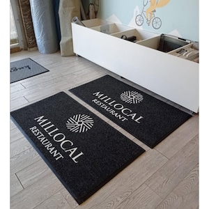 May include: Two black welcome mats with the text "MILLOCAL RESTAURANT" and a stylized logo in white.