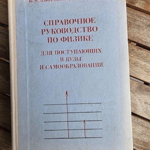 Peut inclure: Un livre à couverture rigide bleu clair intitulé "СПРАВОЧНОЕ РУКОВОДСТВО ПО ФИЗИКЕ ДЛЯ ПОСТУПАЮЩИХ В ВУЗЫ И САМООБРАЗОВАНИЯ" par B.M. Yavorsky et Y.A. Seleznev. La couverture présente du texte rouge et un graphique de lignes horizontales avec deux flèches.