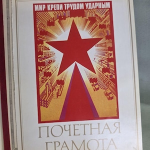 May include: A vintage poster with a red star and text in Russian. The poster features a red star at the center, with a red and yellow industrial scene. The text at the bottom reads "POЧETHАЯ ГРАMOTA".