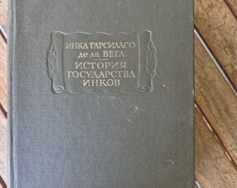 Könnte beinhalten: Ein olivgrünes Vintage-Buch mit geprägtem Text in einem dekorativen Rahmen. Der Titel des Buches, in einer Fremdsprache, ist auf dem Einband zu sehen. Das Buch liegt auf einer Holzoberfläche.