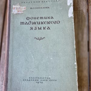 以下が含まれることがあります： 1949年にソ連科学アカデミーから出版された、V.S.ソコロワ著の「Фонетика таджикского языка」というタイトルの薄緑色のハードカバー本。表紙には摩耗の跡があり、端のほつれや小さな紙のラベル、キリル文字のテキストが見られる。