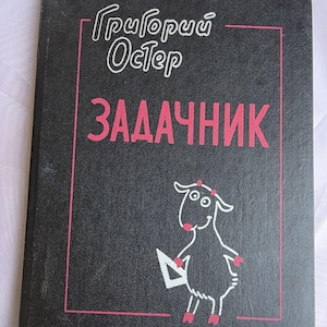 May include: A black hardcover book with pink text and a white line drawing of a goat holding a triangle. The cover features the Cyrillic text "Григорий Остер" and "ЗАДАЧНИК" enclosed within a thin pink rectangular border on the front cover.