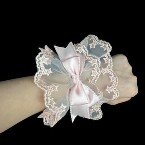 Romantic pink lace wrist cuff with soft bow and layered ruffles for elegant styles