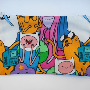 May include: A white zippered pouch with a colorful print of characters from the animated television series Adventure Time. The characters include Finn the Human, Jake the Dog, Princess Bubblegum, and BMO.