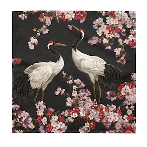 以下が含まれることがあります： 桜の花の中で、赤い頭のマークが付いた2羽の白い鶴が描かれた正方形の装飾布。背景は黒で、微妙な波模様があります。花はピンクと赤です。