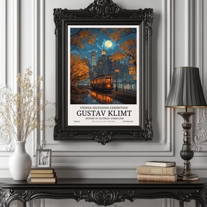 May include: A framed art print featuring a cityscape with a tram, trees, and a full moon. The print is in a black ornate frame. Text on the print reads "VIENNA SECESSION EXHIBITION GUSTAV KLIMT HISTORY OF AUSTRIAN SYMBOLISM". The print is displayed on a black table.