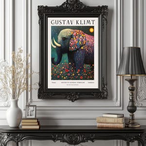 Pode incluir: Uma impressão artística emoldurada com um elefante com um padrão floral colorido, em um fundo escuro. A impressão é intitulada "GUSTAV KLIMT" e inclui texto sobre a história do simbolismo austríaco. A moldura é preta.