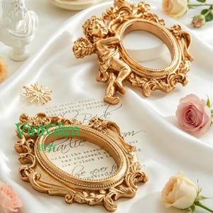 Può includere: Due cornici dorate ornate con aperture ovali. Una cornice presenta una figura di cherubino. Le cornici sono su una superficie di raso bianco con accenti floreali. Il testo "VintSlim" è visibile sulla cornice.