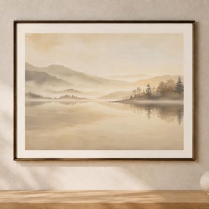 Könnte beinhalten: Ein gerahmter Landschaftsdruck mit einem ruhigen See, der neblige, geschichtete Berge in Beige-, Creme- und sanften Brauntönen widerspiegelt. Das Kunstwerk zeigt ein ruhiges Gewässer mit einem bewaldeten Ufer auf der rechten Seite in einem dunklen Rahmen.