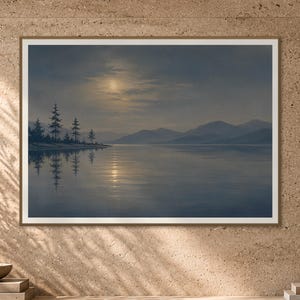 May include: A framed landscape print depicting a serene lake at night under a full moon. The scene features dark silhouettes of pine trees on the left shore, distant mountain ranges, and a calm water surface reflecting the moonlight in soft blue tones.