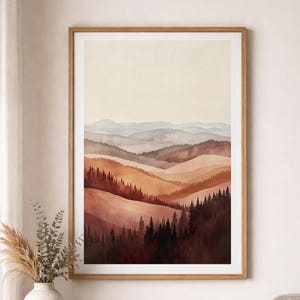 Könnte beinhalten: Aquarell-Kunstdruck mit einer geschichteten Hügellandschaft in Orange-, Braun- und Grautönen, mit einem Wald aus dunklen Bäumen im Vordergrund. Das Kunstwerk ist in einem hellbraunen Holzrahmen gerahmt.