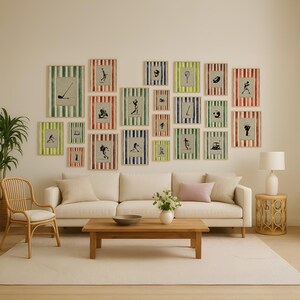Könnte beinhalten: Eine Sammlung gerahmter Kunstdrucke mit Golfmotiven. Jeder Druck hat einen gestreiften Rand in verschiedenen Farben, darunter Grün, Rot und Blau. Die Kunstwerke sind über einem weißen Sofa und einem Holztisch ausgestellt.