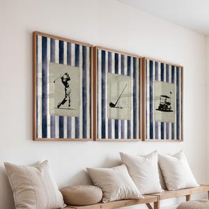 May include: Three framed golf-themed prints. Each print features a different golf image: a golfer swinging, a golf club, and a golf cart. The prints are set against a blue and white striped background and framed in wood.