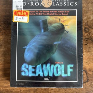 May include: A sealed CD-ROM game titled "SEAWOLF" featuring a submarine graphic. The box has a "sale" sticker with a price of $9.99. The game is part of the Electronic Arts D'ROM Classics series.