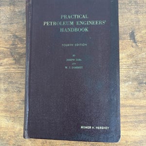 May include: A dark purple, hardcover book titled "PRACTICAL PETROLEUM ENGINEERS' HANDBOOK" in green lettering. The book is the fourth edition, by Joseph Zaba and W. T. Doherty, with Homer H. Hershey's name at the bottom.
