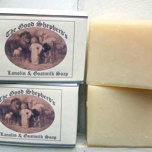 May include: Two rectangular bars of off-white soap next to two identical white boxes labeled The Good Shepherd's Lanolin & Goatmilk Soap, featuring an oval illustration of a child surrounded by various animals including a lion and a lamb.