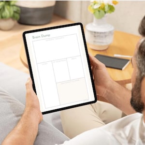 Könnte beinhalten: Ein digitales Tablet, das eine weiße Planervorlage mit der Überschrift Brain Dump anzeigt. Das Layout enthält Abschnitte mit den Bezeichnungen Random Thoughts, To-Dos, To Schedule, Ideas und Decisions to Make in einem schwarzen Raster.