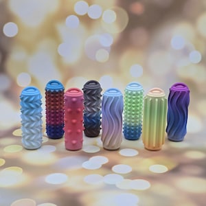 May include: A selection of massage rollers in a range of colours, including blue, red, pink, grey, green, and purple. Each roller features a distinct textured design, such as wave patterns, spikes, and ridges. The rollers are cylindrical and stand upright.