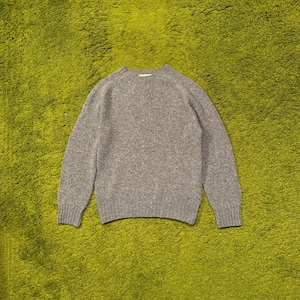May include: A heather gray sweater with a crew neck and long sleeves. The knitwear has ribbed cuffs and hem. The sweater is made of a soft, textured material.