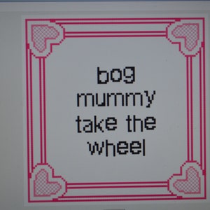 May include: A pink heart-shaped frame with a white background and the text "bog mummy take the wheel" inside.