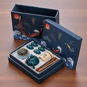 Op de afbeelding: Een donkerblauwe geschenkverpakking met een theemaatje. De set bevat een theepot, kopjes, een wierookbrander en theeaccessoires. De doos en tas hebben golf- en koi-visontwerpen.