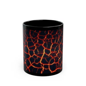 Può includere: Una tazza cilindrica in ceramica con una superficie esterna nera decorata con un motivo a lava incrinata di colore arancione e rosso brillante che copre l'intero corpo, contrastata da un interno nero solido e una finitura liscia e lucida.