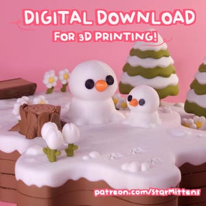 May include: A whimsical 3D-printed winter scene featuring two snowmen with black eyes and orange beaks, surrounded by miniature trees and flowers. The scene is set on a white, snow-covered base with a brown border, all against a pink backdrop. Text reads "DIGITAL DOWNLOAD FOR 3D PRINTING!"