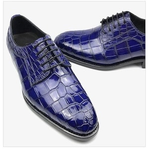 May include: A pair of blue leather dress shoes with a crocodile pattern. The shoes have a lace-up closure and a pointed toe.