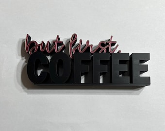 May include: Black and pink wooden sign with the phrase "but first, COFFEE". The words "but first" are in a cursive font with a pink glitter effect. The word "COFFEE" is in bold, block letters.