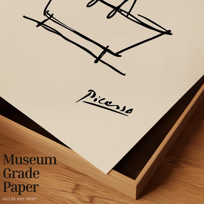 May include: A framed print featuring a black line drawing and the signature "Picasso." The words "Museum Grade Paper" are printed in a stacked format. The artwork is set in a wooden frame.