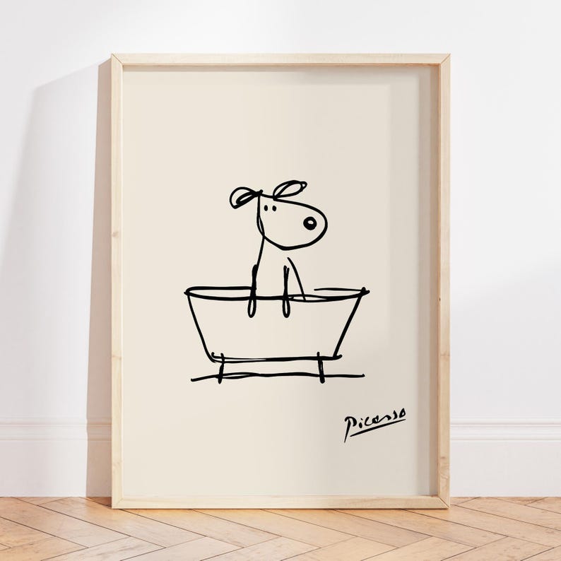 May include: A framed print featuring a whimsical line drawing of a dog in a bathtub. The black ink illustration is set against a cream background, with the artist's signature in the lower right corner. The artwork is in a light wood frame.
