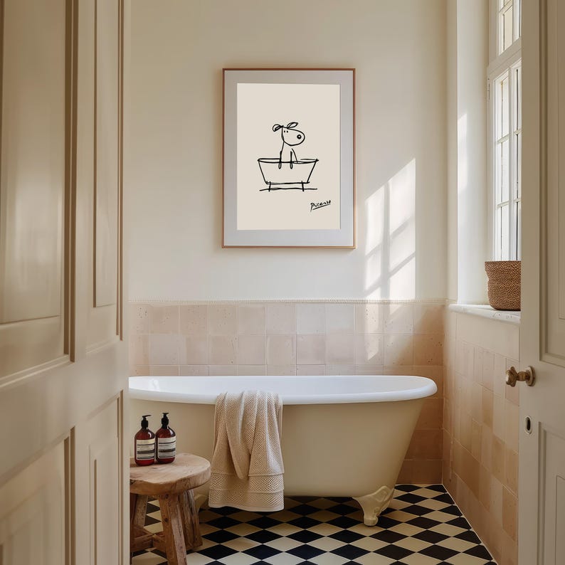May include: A framed art print featuring a minimalist line drawing of a dog in a bathtub. The artwork is in black on a cream background, with the artist's signature. The bathroom has a clawfoot tub, a wooden stool, and a black and white checkered floor.