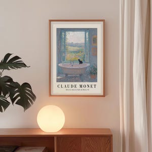 May include: A framed print of Claude Monet's "R&ecirc;veries dans la Salle de Bain n&deg;11" depicting a bathtub with a black cat, overlooking a landscape. The print is in a wooden frame, with text at the bottom.