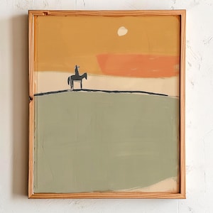 以下が含まれることがあります： 木製フレームに入った抽象画。夕焼けを背景に、丘の上に馬に乗ったシルエットのライダーが描かれています。オレンジと黄色の色合い。絵画の下部はくすんだ緑色です。