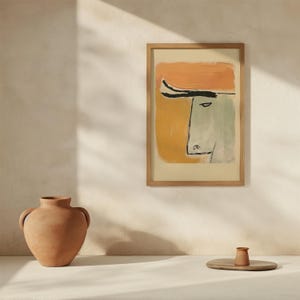 Op de afbeelding: Abstracte kunstprint in een houten lijst. Het kunstwerk toont een gezicht met een oranje hoed en een gele en groene achtergrond. Een terracotta vaas en een kleine houten dienblad met een terracotta kopje staan op de voorgrond.