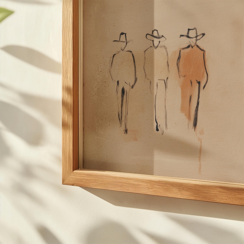 Puede incluir: Una obra de arte enmarcada que presenta un boceto de tres figuras con sombreros de vaquero. Las figuras est&aacute;n representadas con l&iacute;neas negras y un toque de sombreado color melocot&oacute;n. La obra de arte est&aacute; encerrada en un marco de madera natural.