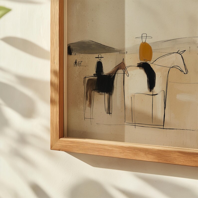 May include: Abstract art print featuring two riders on horseback, rendered in a minimalist style with black and brown ink. The riders wear hats and are set against a neutral background with a mountain silhouette. The artwork is framed in a natural wood frame.