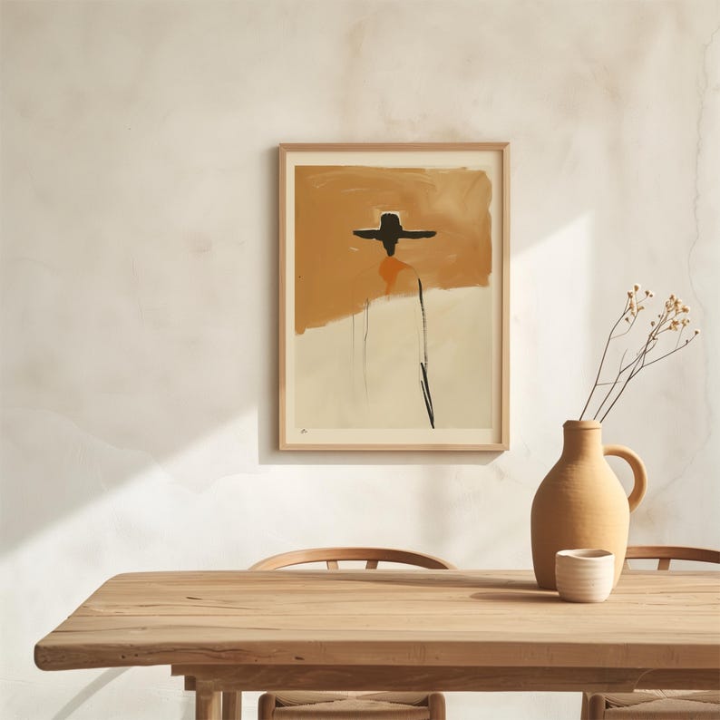 K&ouml;nnte beinhalten: Abstrakter Kunstdruck in einem Holzrahmen. Das Kunstwerk zeigt eine Figur mit schwarzem Hut vor einem Hintergrund aus Orange- und Cremet&ouml;nen. Eine Terrakotta-Vase und eine kleine wei&szlig;e Tasse stehen auf einem Holztisch.