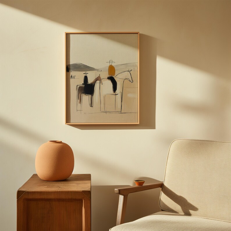 May include: A framed abstract art print depicting two riders on horseback in a minimalist style. The artwork features black and brown brushstrokes against a beige background, with a light wooden frame. A terracotta vase sits on a wooden side table.